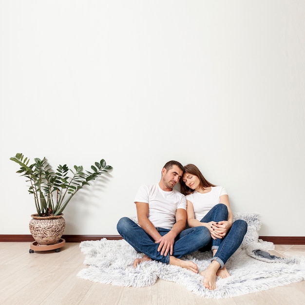 Free photo full shot young couple sitting on floor