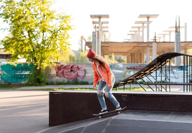 Бесплатное фото Молодая девушка в полный рост на скейтборде на открытом воздухе