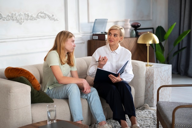 Full shot young girl talking to therapist