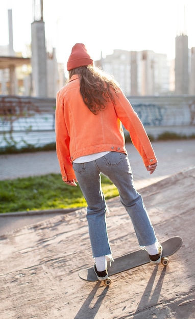 Ragazza del colpo pieno con il pattino all'esterno