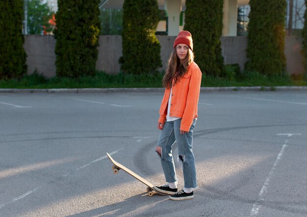 屋外でスケートボードとフルショットの若い女の子