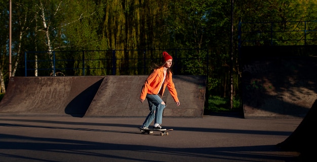 Молодая девушка в полный рост со скейтбордом на улице
