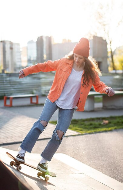 Молодая девушка в полный рост со скейтбордом на улице