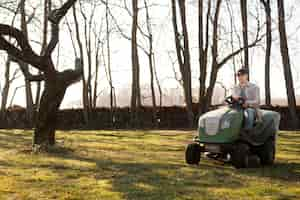 Foto gratuita giovane del colpo pieno che guida la falciatrice da giardino