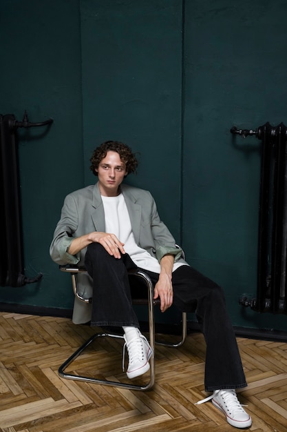 Full shot young man posing on chair