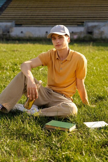 풀 샷 젊은 남자가 잔디에 앉아