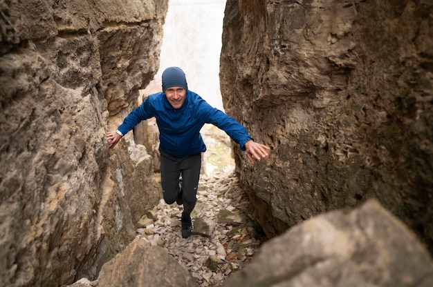 Бесплатное фото Молодой человек в полный рост идет через скалы