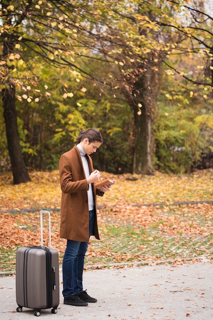 Free photo full shot young man with luggage in the park