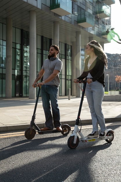 Free photo full shot young people on electric scooters outdoors