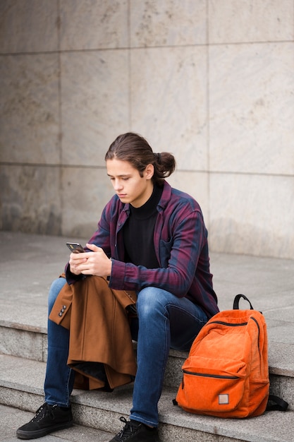 Full shot young tourist checking his phone