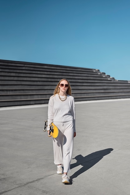 Foto gratuita skateboard della holding della giovane donna del colpo pieno