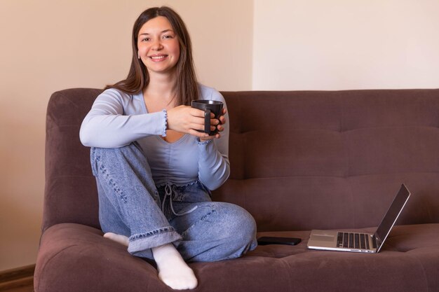 カメラと笑顔を見て茶色のコーチに座っている美しい女性の全景