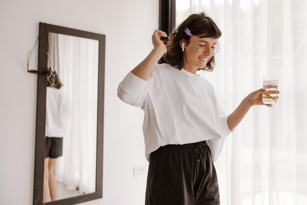 Full view of smiling woman with gel patches dancing at home listening music