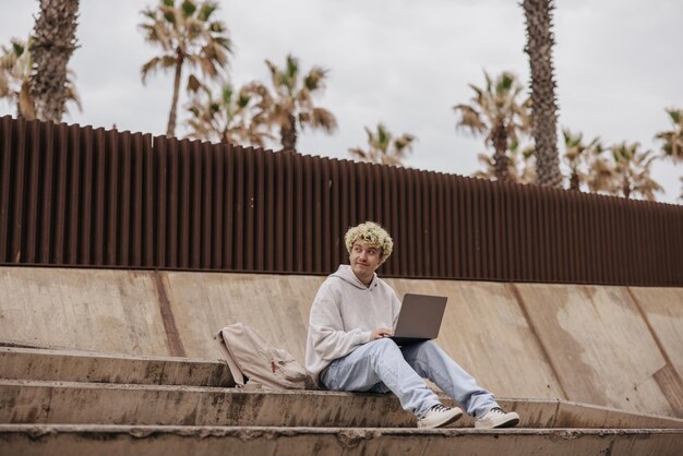 Full view of stylish man sitting on the floor with laptop