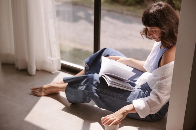 Full view of woman looking at book at home