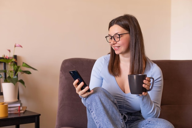 Full view of woman sitting at home look at phone