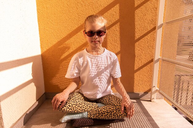 Full view of young sweetie kid looking at camera in orange sunglasses