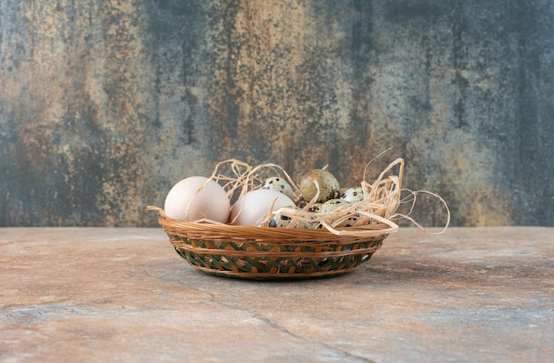 Free photo full wicker basket with quail eggs on marble