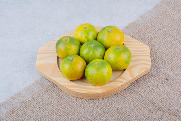 Full wooden plate of sour tangerines on white background. High quality photo