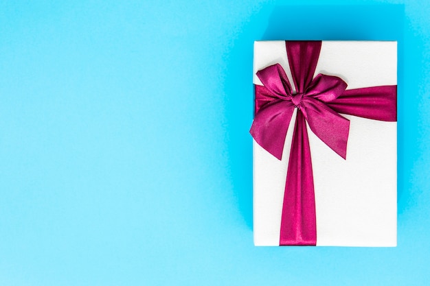 Free photo full wrapped gift with ribbon blue background