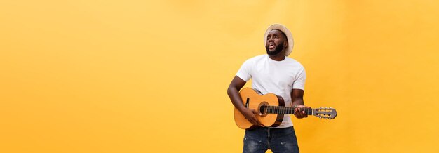 Fulllength photo of excited artistic man playing his guitar in casual suite isolated on yellow backg