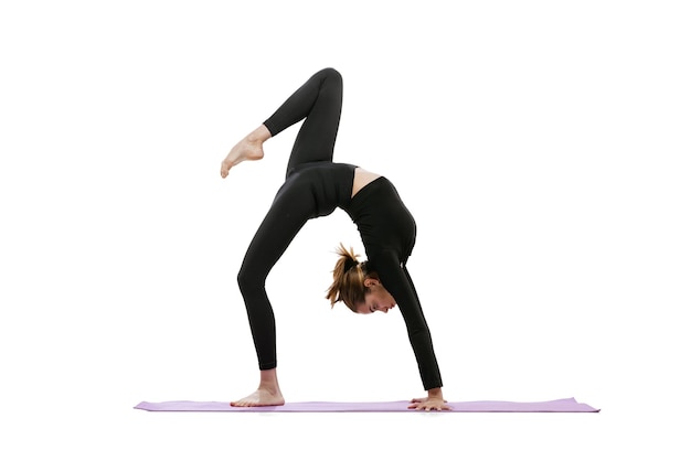 Fulllength portrait of younf sportive girl training doing yoga and stretching exercises isolated over white background