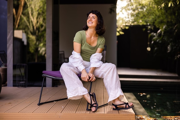 Fulllength view of cute woman sitting on the chair and looking away