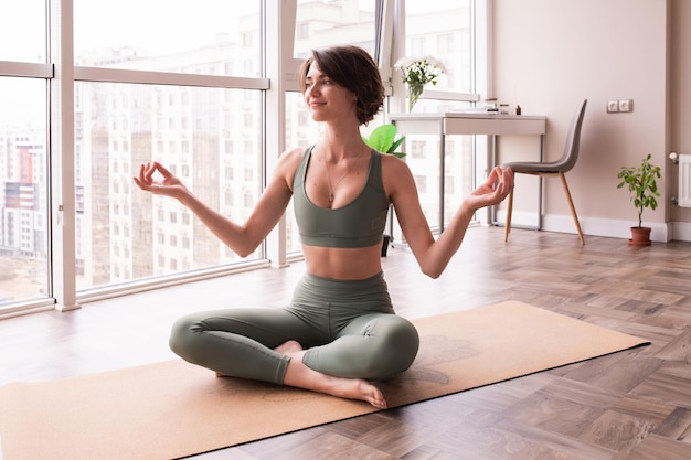 Вид в полный рост женщины, сидящей в позе йоги