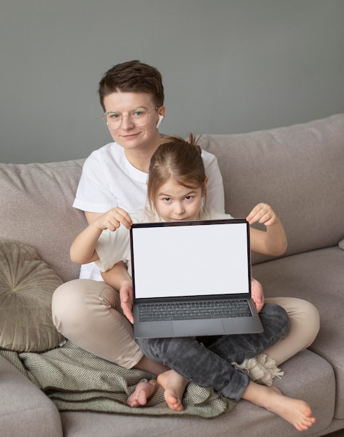 Полный снимок родителей и детей на диване с ноутбуком