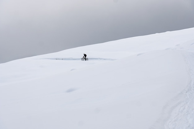 눈 덮인 산에서 자전거를 타는 완비된 사이클리스트