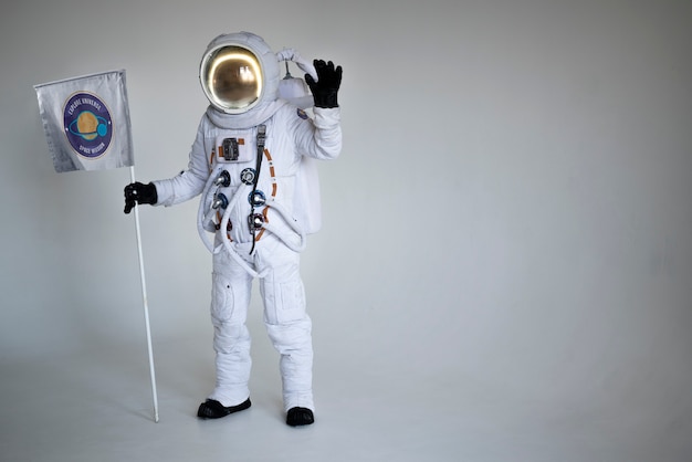 Fully equipped male astronaut holding a flag and waving