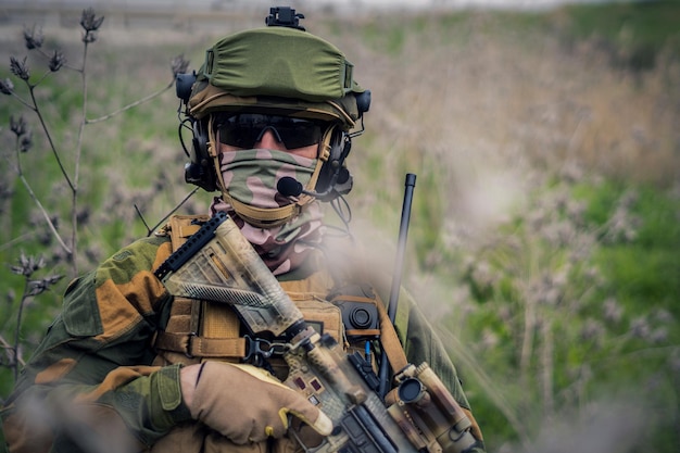 Fully equipped soldier in the camouflage uniform holding an assault rifle