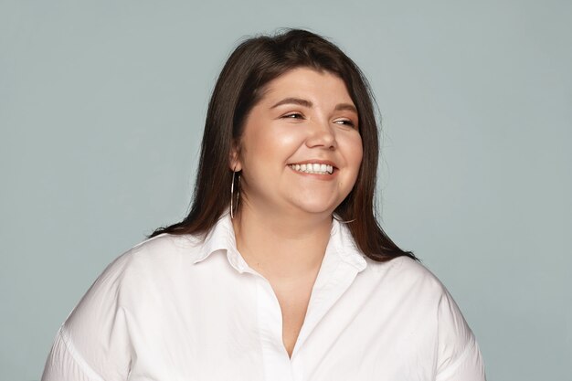 Fun, joy, happiness and positive emotions. Portrait of happy emotional young European dark haired female employee with chubby cheeks and curvy body being in good mood, laughing at funny joke