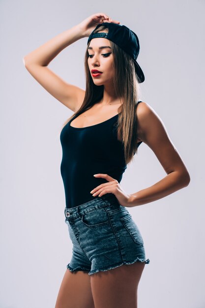 ファンキーなスタイルの美しさ。灰色の壁に立っている間眼鏡とファンキーな帽子の美しい若い女性の肖像画