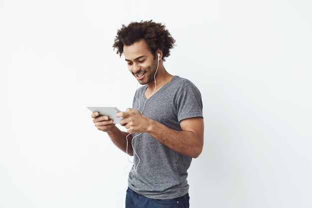 Free photo funny african man in headphones smiling laughing looking at tablet.