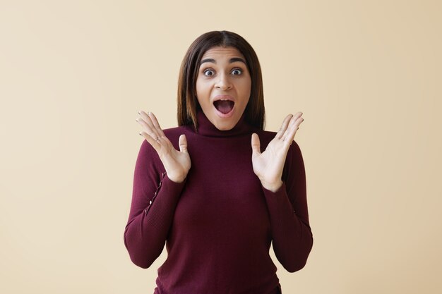 funny astonished young African American female shouting in excitement while receiving birthday gift, gesturing and widening eyes in full disbelief. Shock and astonishment