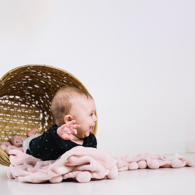 Foto gratuita bambino divertente che si trova in cestino rovesciato