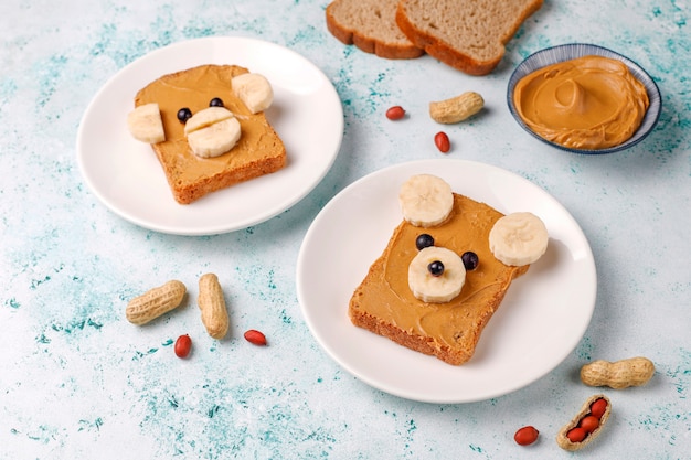 Funny bear and monkey face sandwich with peanut butter, banana and black currant, top view