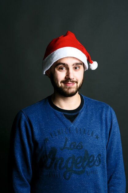 Funny bearded man in red Christmas hat crosses hands on his chest 