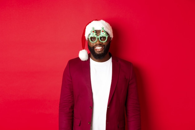 Free photo funny black man in santa hat and party glasses celebrating christmas