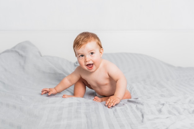 Funny blonde baby on a bed