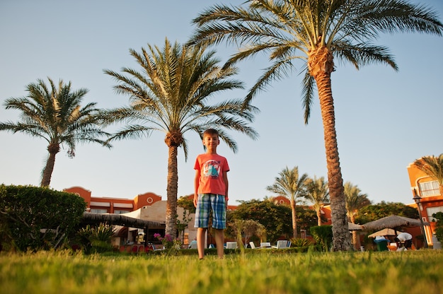 手のひら​の​近く​に​立っている​エジプト​の​リゾート​の​庭​で​面白い​男の子​。