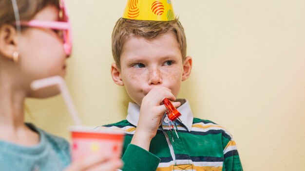 Funny boy blowing noisemaker on party