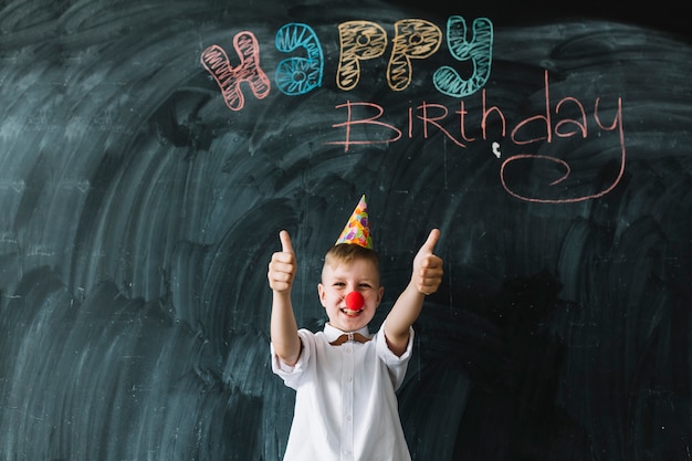 Free photo funny boy gesturing thumb-ups on birthday party