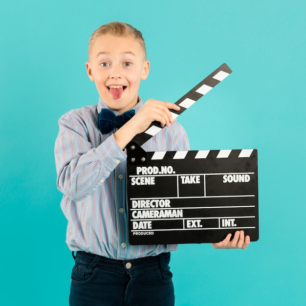 Free photo funny boy holding clapperboard front view