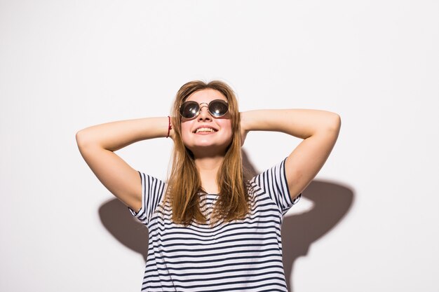 Funny casual teenager woman wearing fashion sunglasses gesturing isolated on a white wall