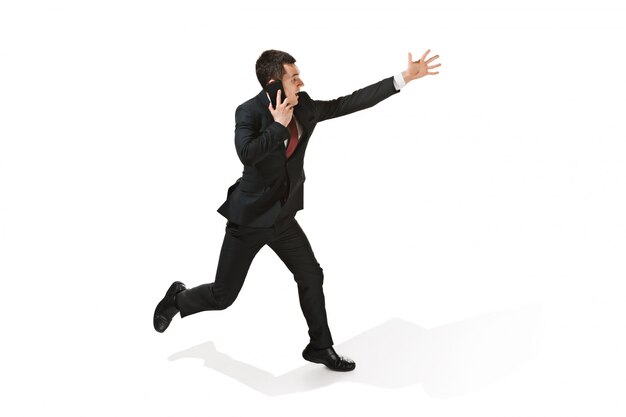 Funny cheerful businessman running and talking on the phone