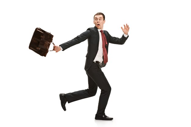 Funny cheerful businessman running over white studio background.