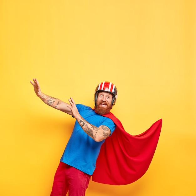 Забавный веселый супергерой-мужчина носит шлем и красный плащ