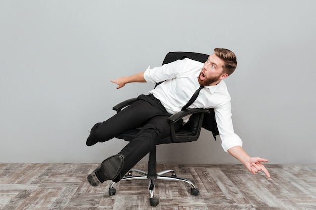 Foto gratuita uomo d'affari pazzo divertente divertendosi mentre era seduto nella sedia da ufficio